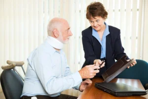 A lawyer handing a pen to an elderly client wearing a neck brace.
