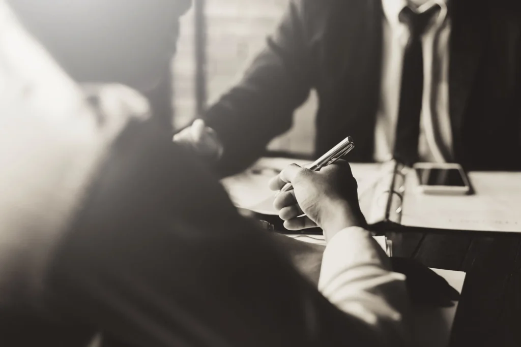 Black and white picture of two businessmen reviewing paperwork.